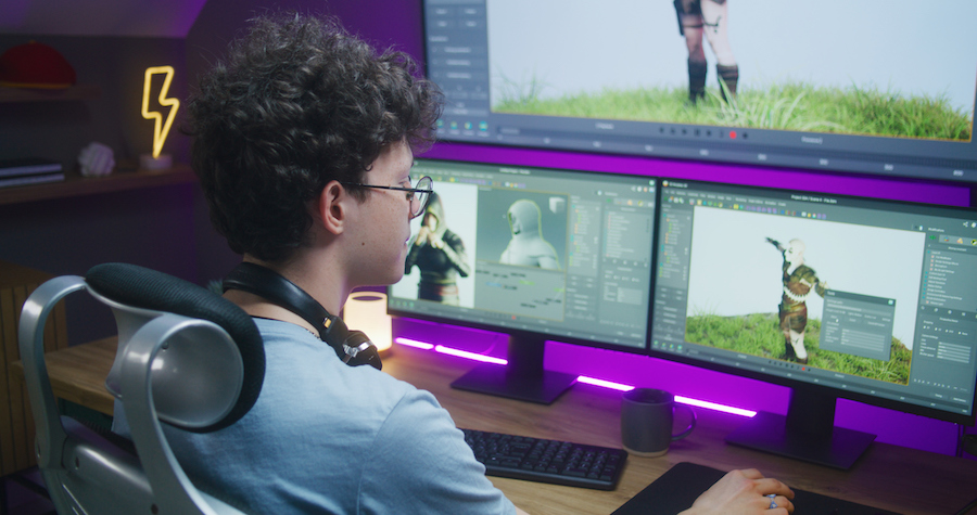 Image of young 3D desisgner at a computer with 3 monitors